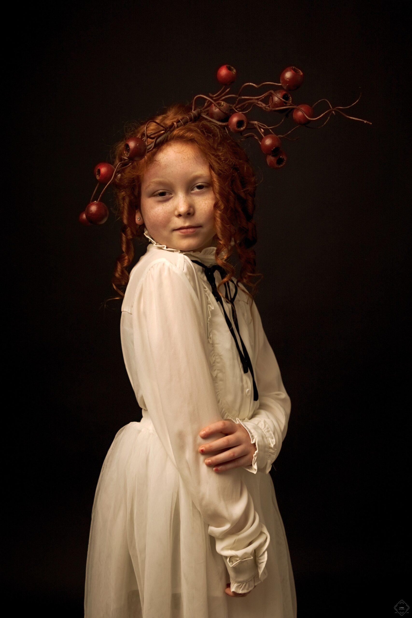 Young girl with red hair and headpiece posing for a vintage portrait