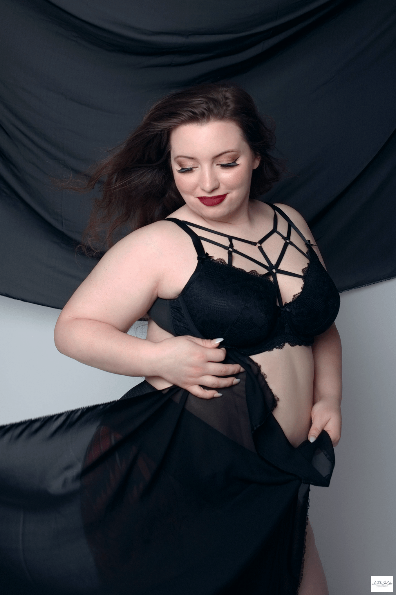 Woman in black bra and Black Sheer fabric posing with red lipstick in her  Boudoir Session