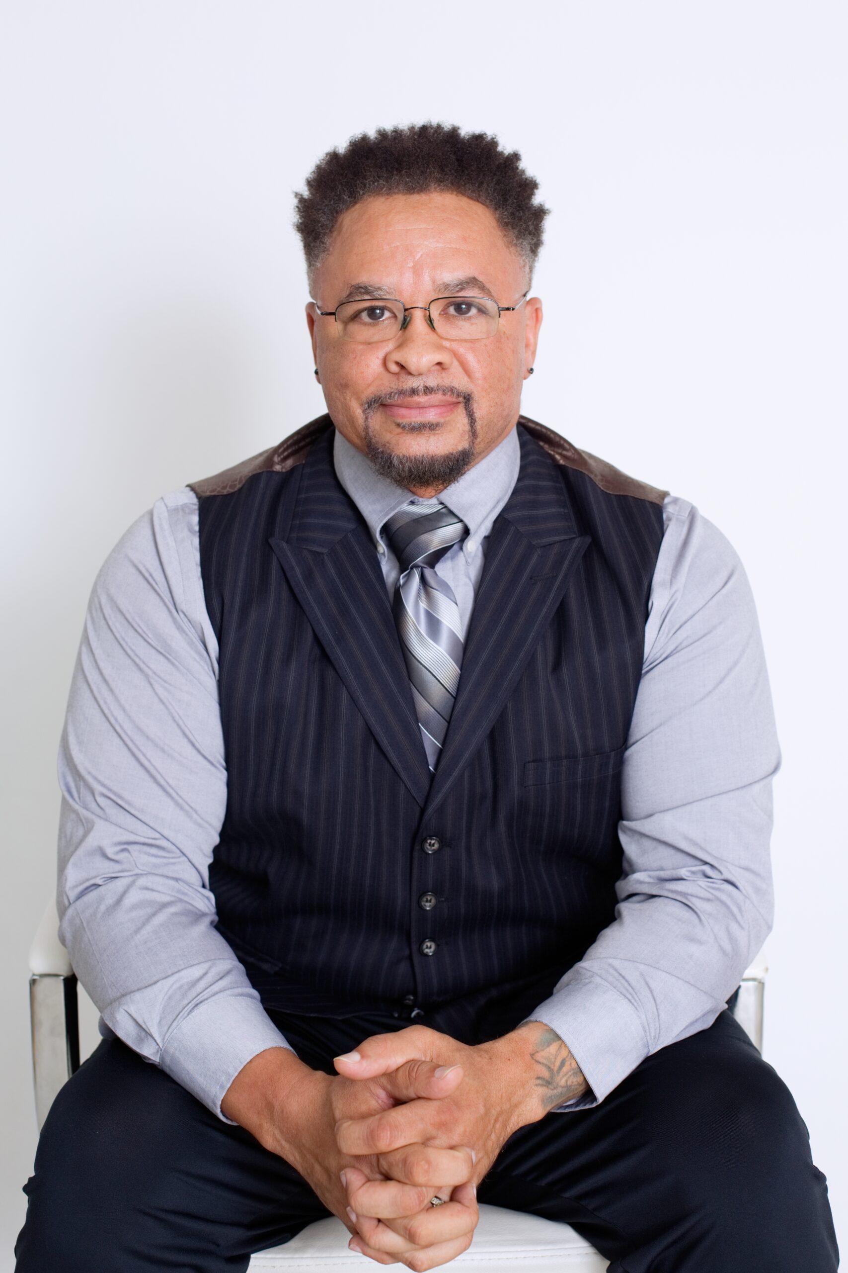 Business man with glasses sitting on chair posing in business attire