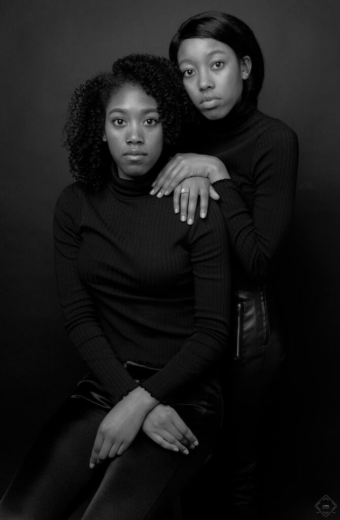 2 sisters posing together in a black and white portrait