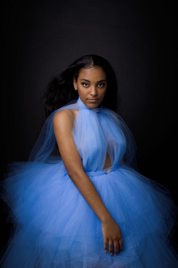 Confident young black girl in blue tulle dress posing for her portrait