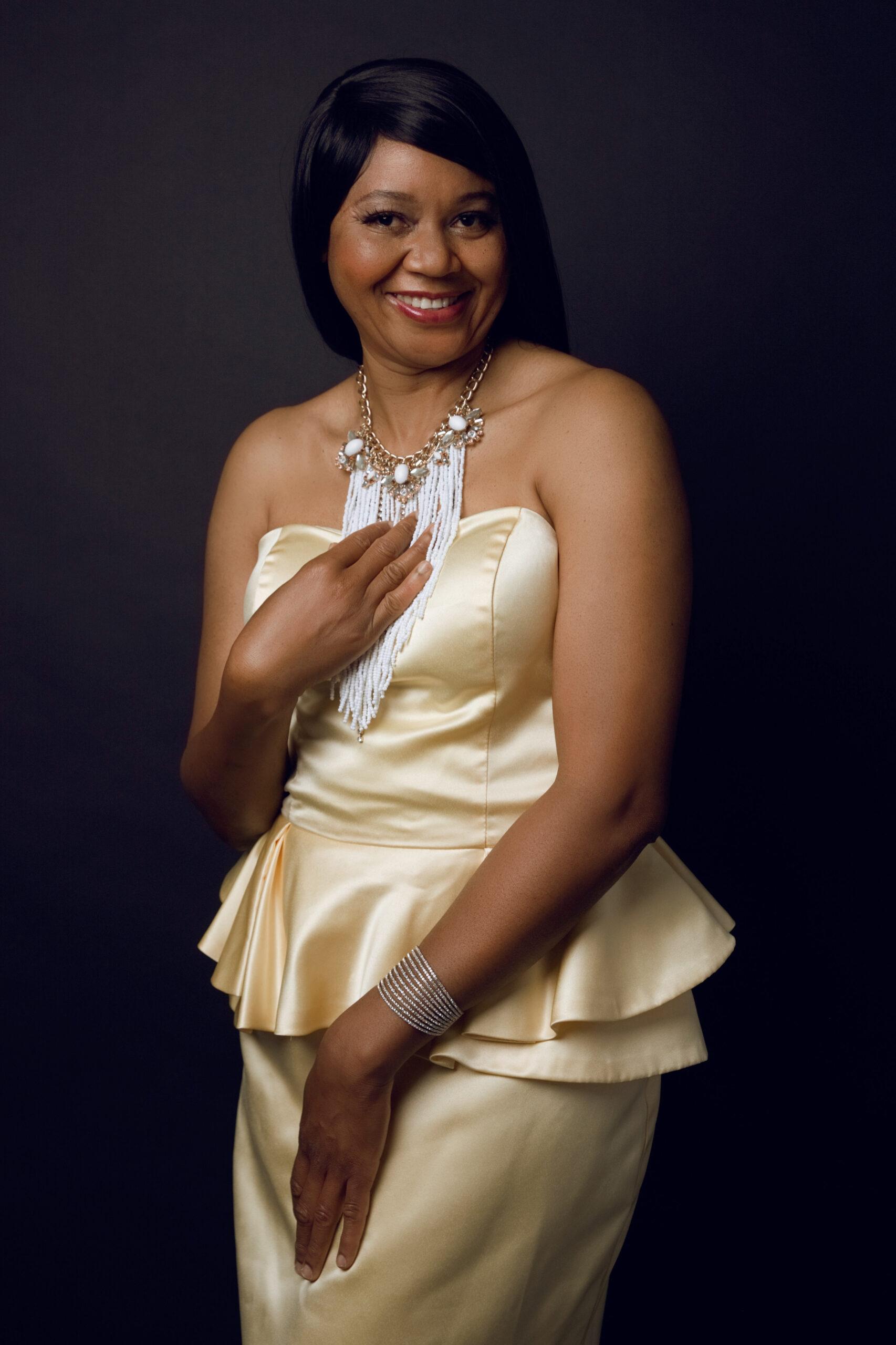 Black woman wearing a yellow satin dress and smiling